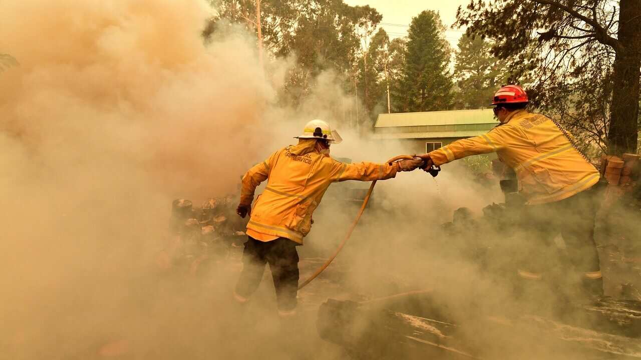 Firefighters hose down a burning woodpile during a bushfire in Werombi, south-west of Sydney.