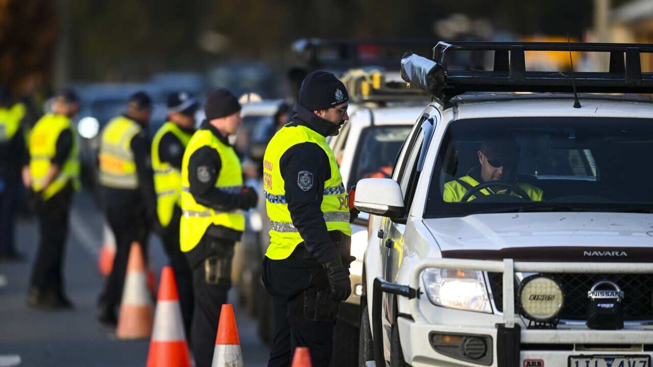 NSW Police officers check cars crossing from Victoria at a border check point in Albury