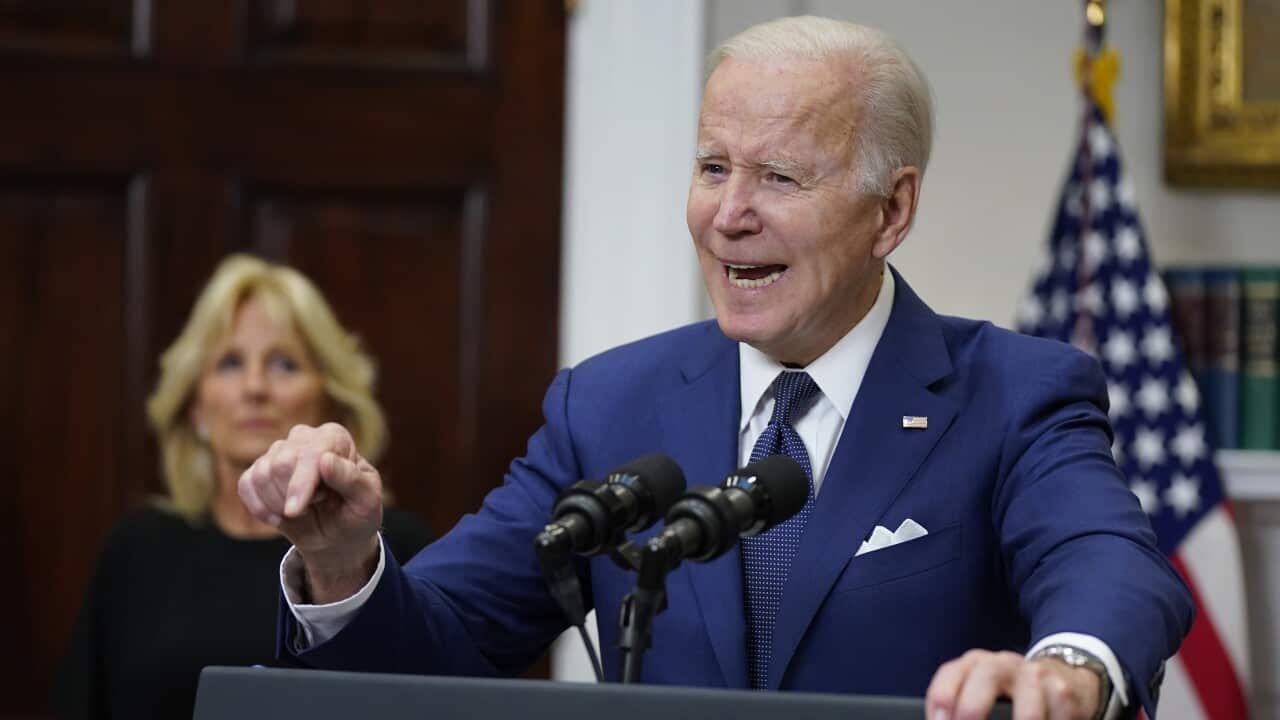 US President Joe Biden speaks from behind a podium as first lady Jill Biden listens