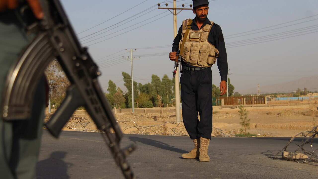 Afghan Police stand guard on a highway leading to Shah Wali Khan district, in Kandahar, Afghanistan