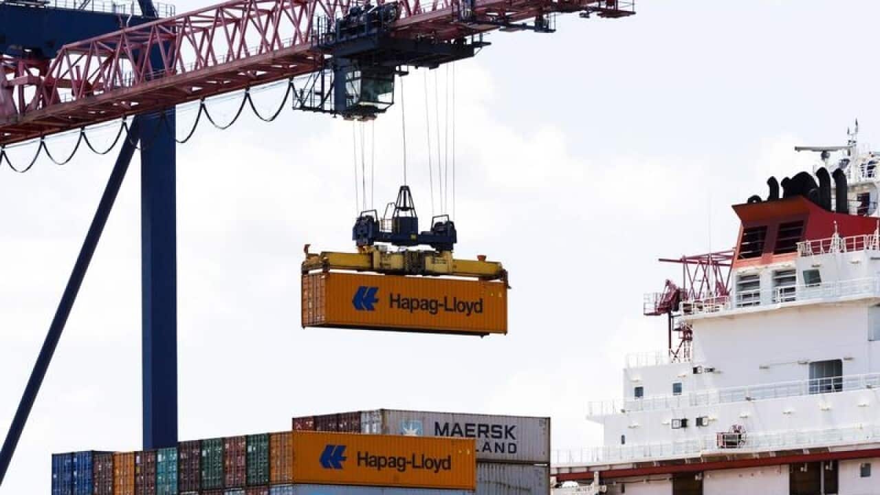 Shipping containers are unloaded from a cargo ship.