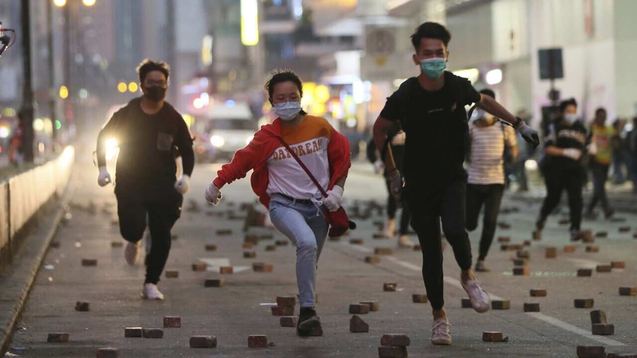 Anti-government protesters flee on a street as riot police vehicle chases in Hong Kong on 19 November, 2019.