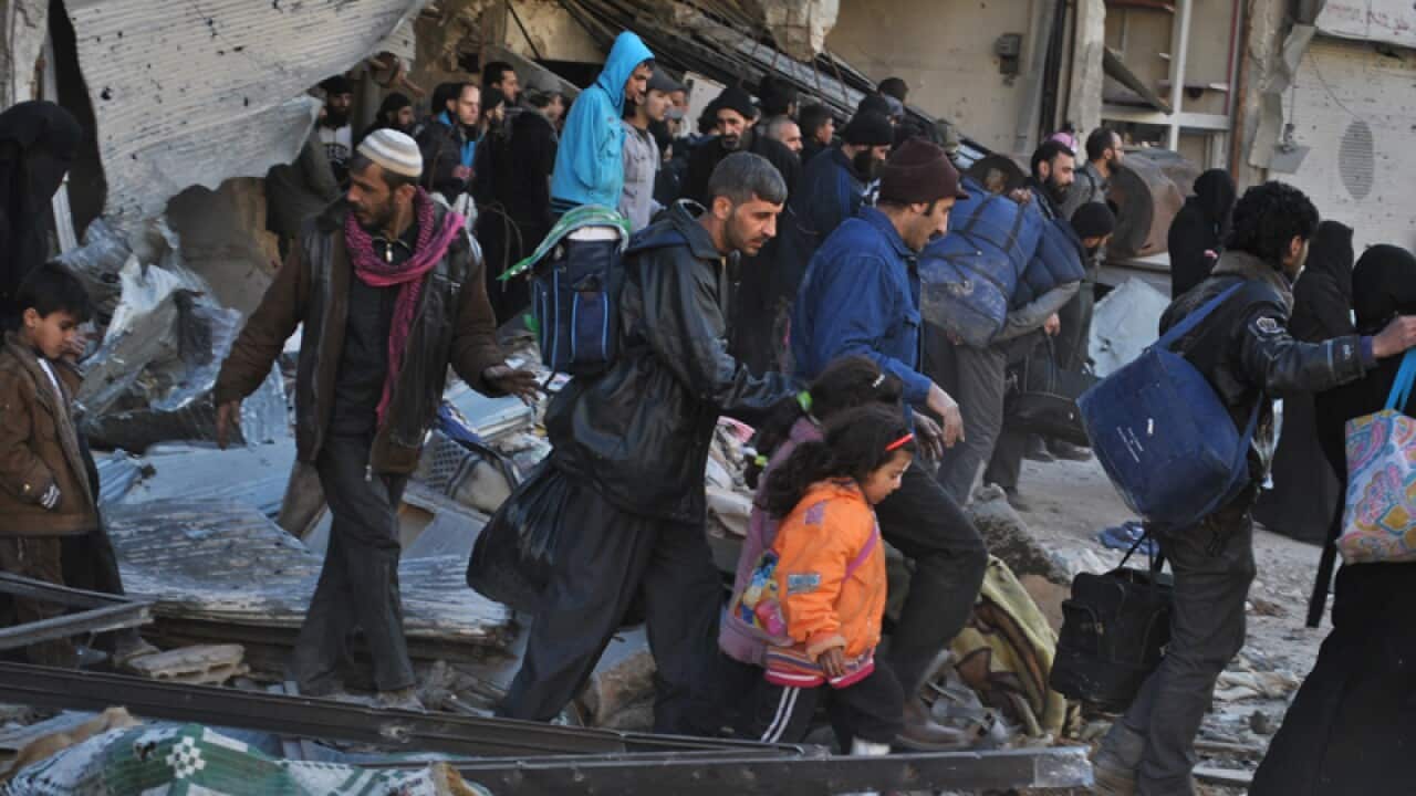 Syrian civilians walks as they are evacuated from Homs