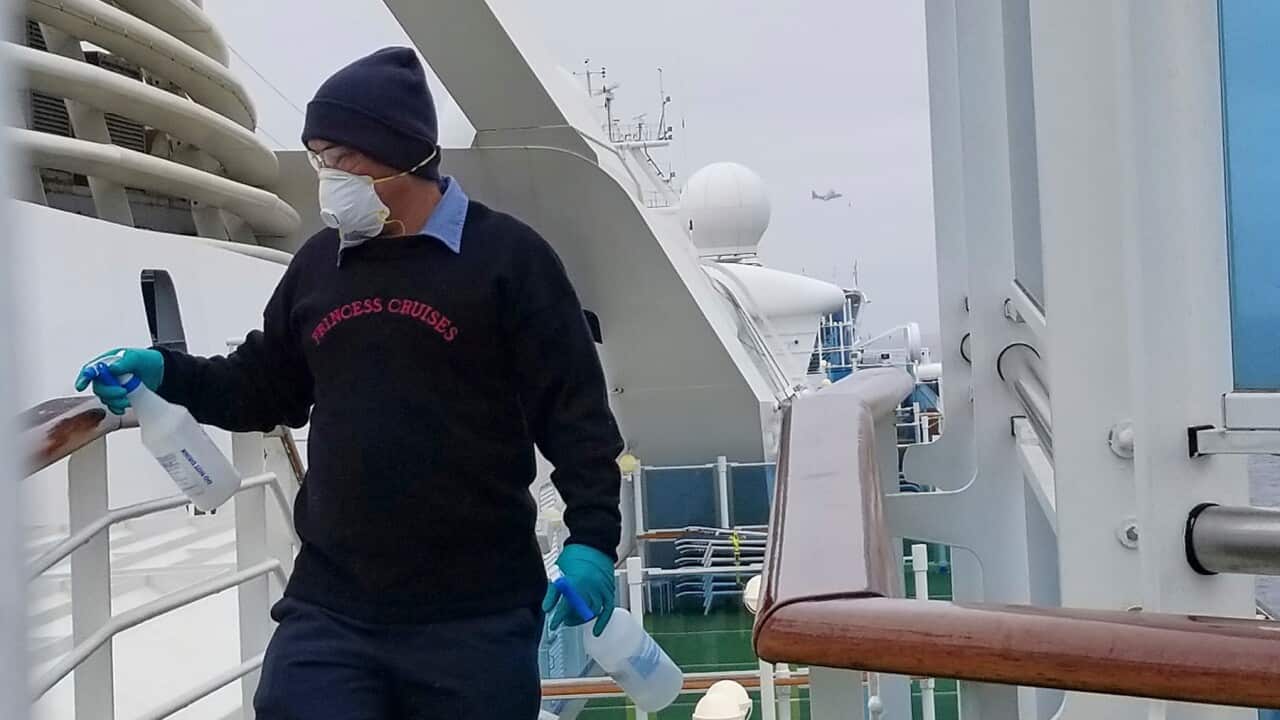 A cruise ship worker cleans a railing on the Grand Princess off the California coast
