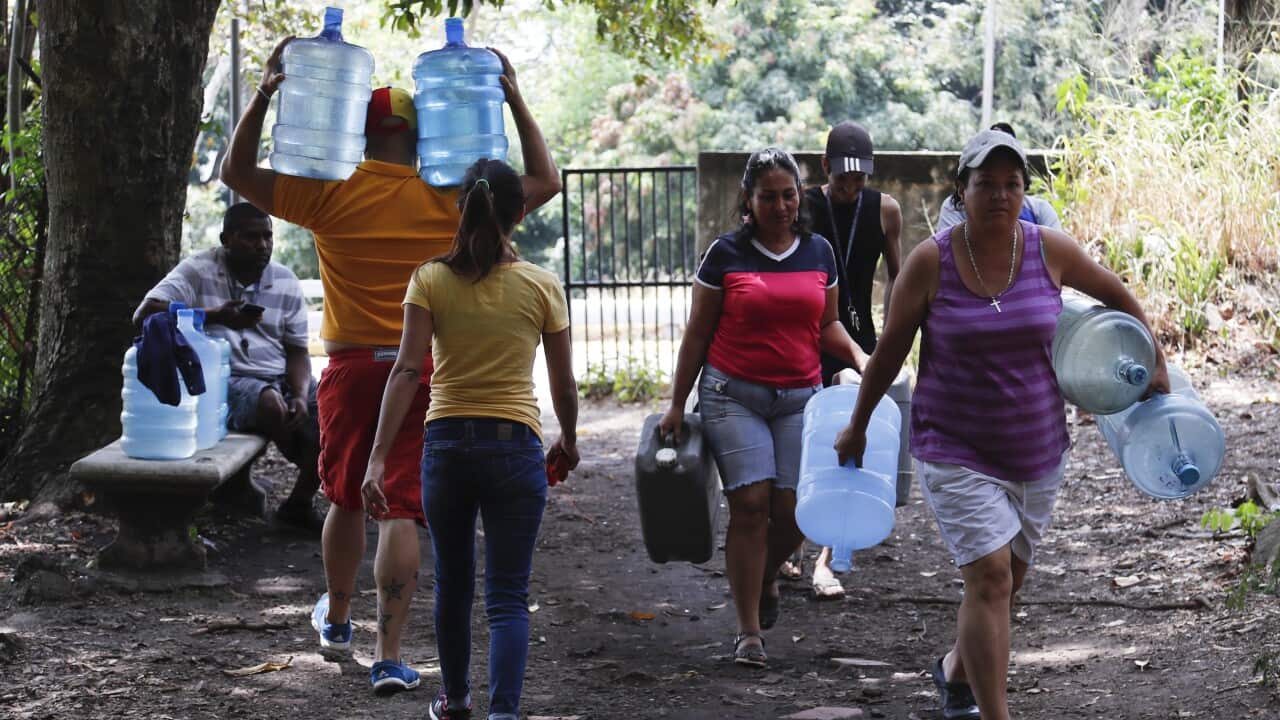 People carry containers to fill with water Avila National Park during rolling blackouts which has cut many off from running water in Caracas