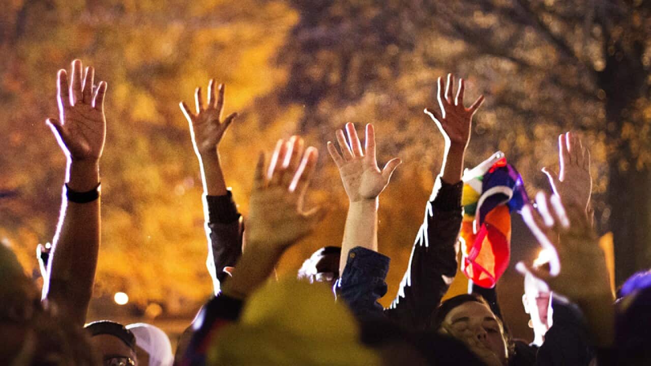Protesters hold up their hands during a protest