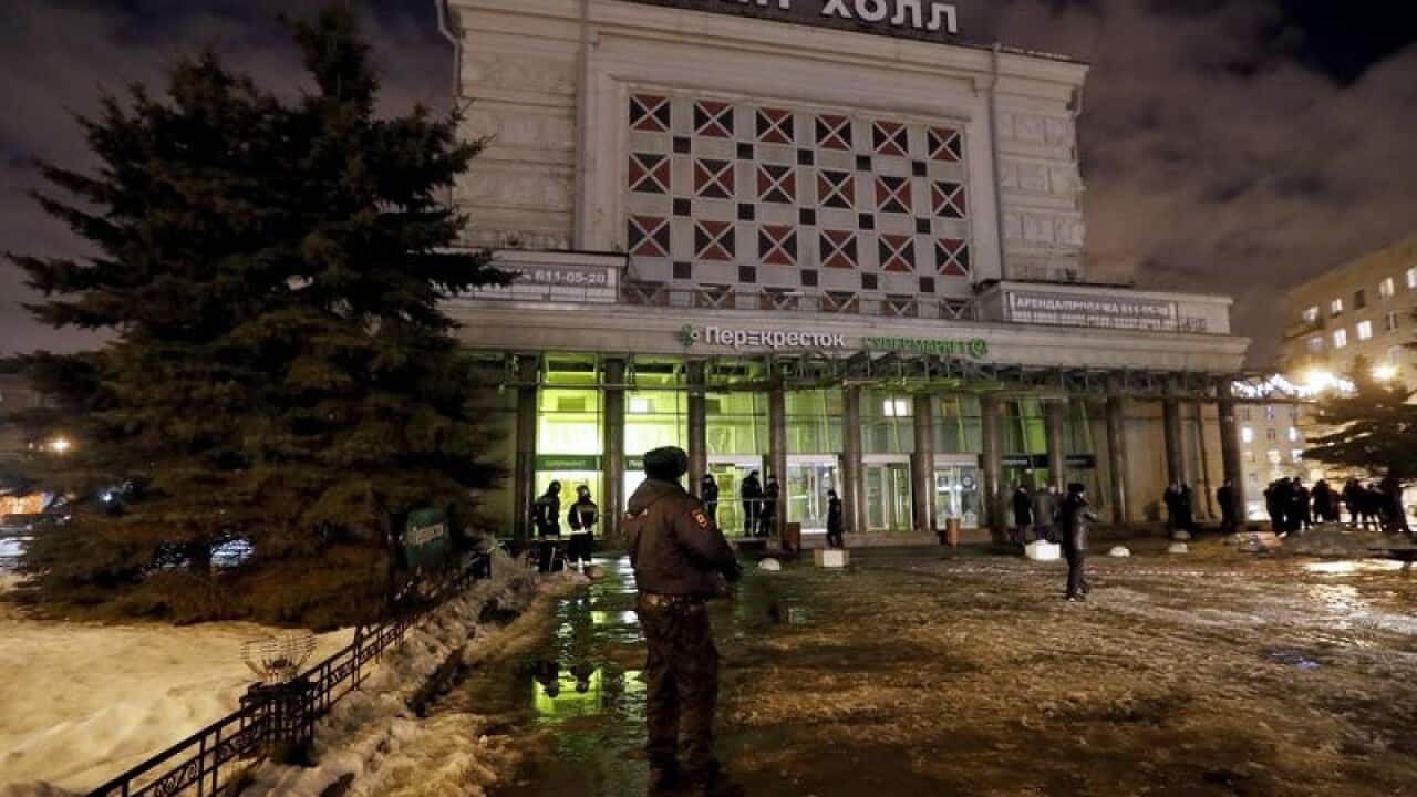 Police officers and firefighters work at the site of an explosion.