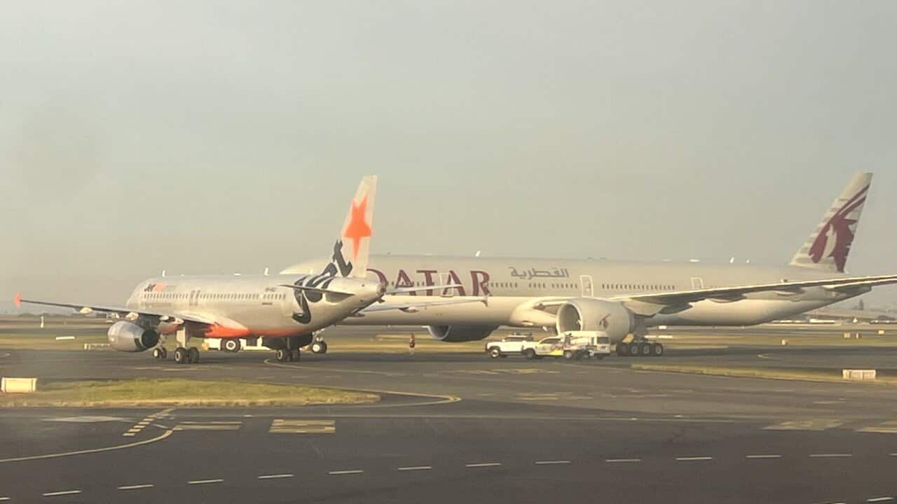 Two planes sit close together on an airport runway.
