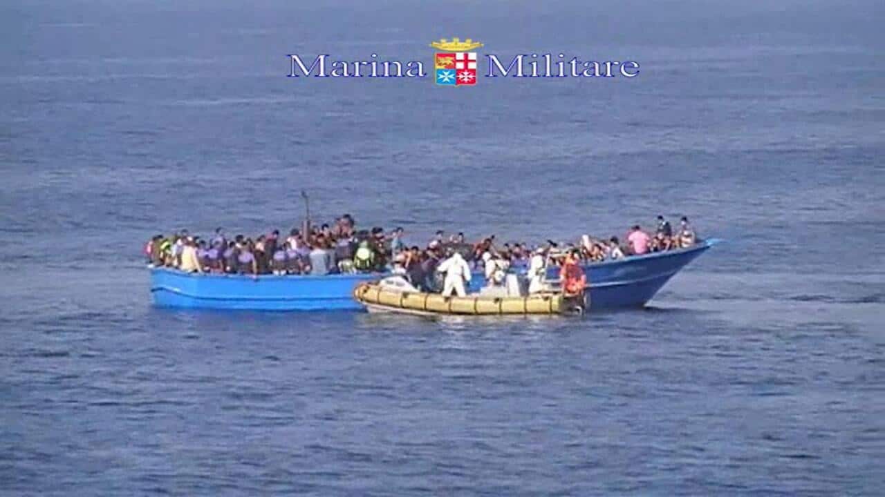 This image taken from video provided by the Italian Navy (Marina Militare) Saturday, Aug. 15, 2015, shows an Italian Navy RIB approaching a fishing boat crowded with migrants off the coast of Libya. (Marina Militare via AP)