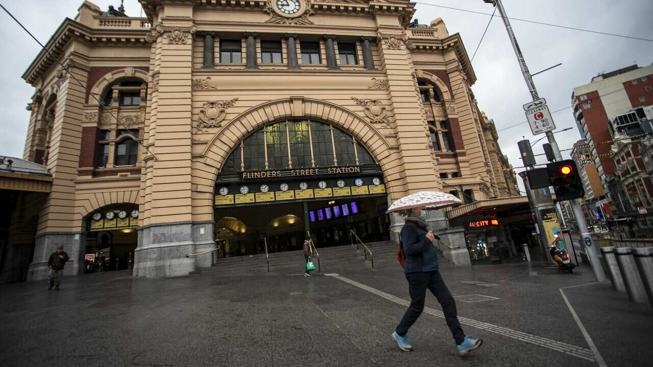 People are seen passing a quiet Flinders Street Station in Melbourne on Tuesday, 20 July, 2021.