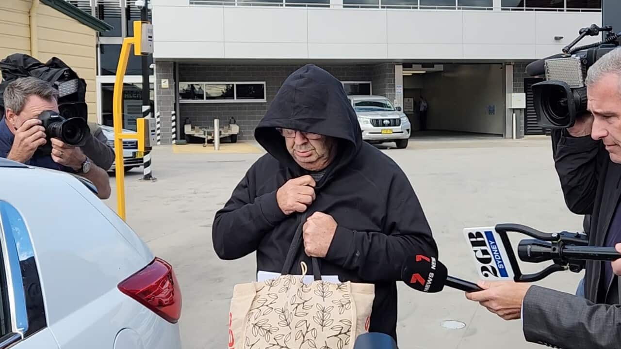 A man in a black hoodie getting into a car