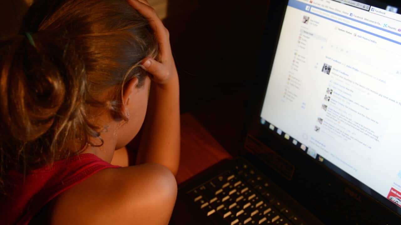 An upset young girl in front of a personal computer.