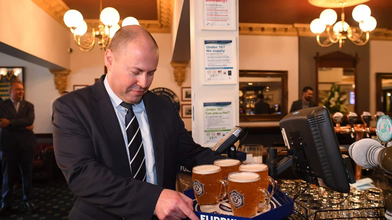 Federal treasurer Josh Frydenberg carries a tray of beer at the Glenferrie Pub in Melbourne,