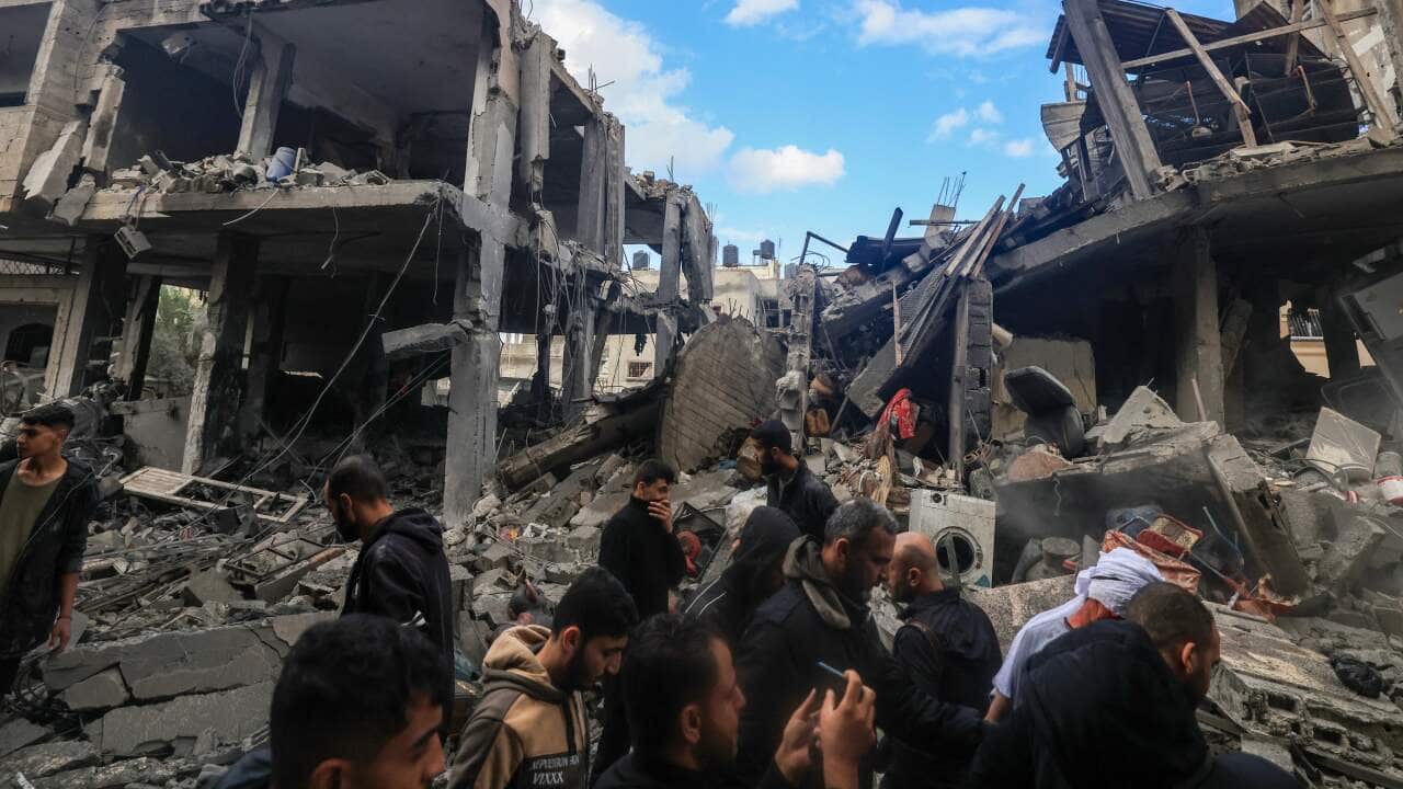 People walking amid the rubble of destroyed buildings.