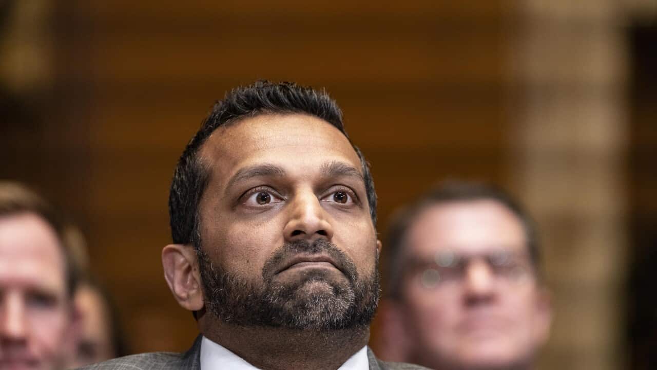 A man wearing a suit looks on with a stern face
