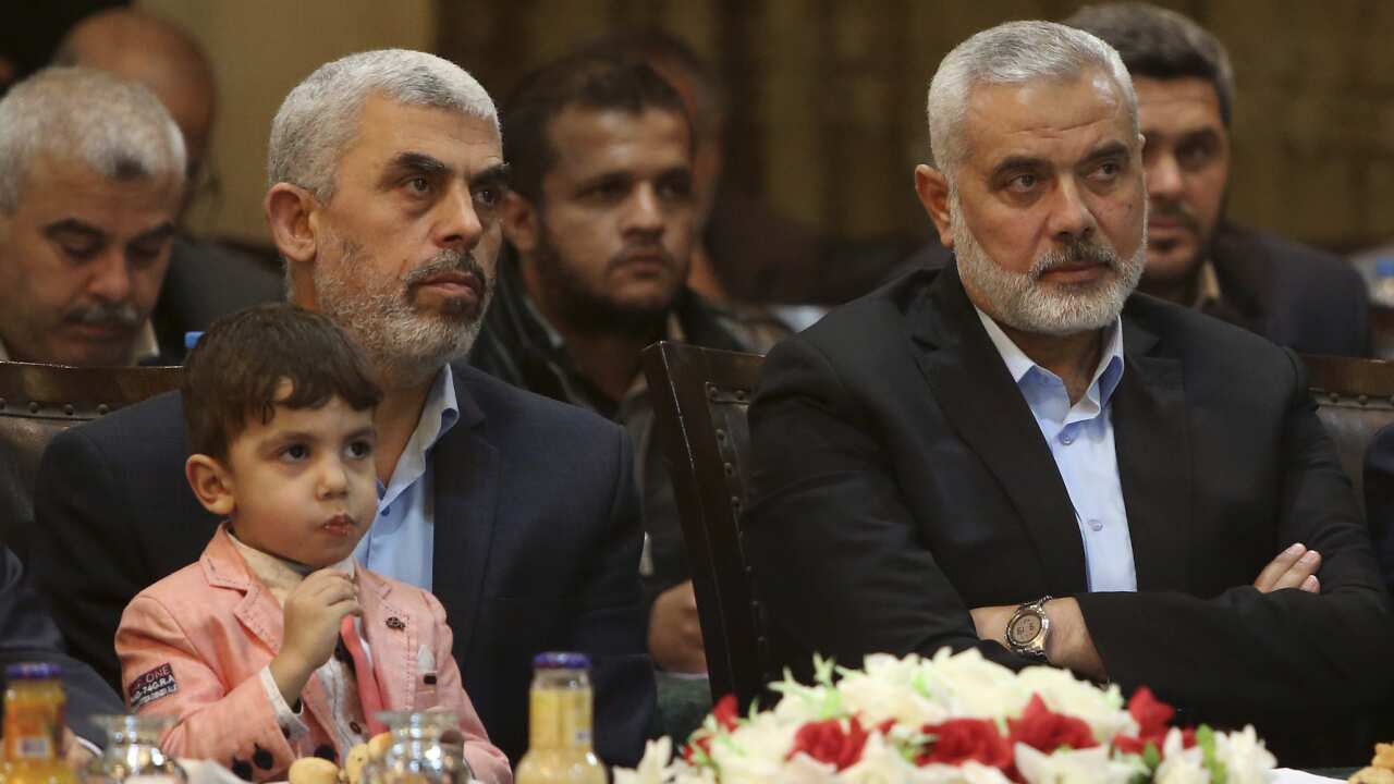In this May 1, 2017, file photo, Gaza leader, Yehya Sinwar, left, holding his son Ibrahim, sits next to Ismail Haniyeh, a former top Hamas official in Gaza