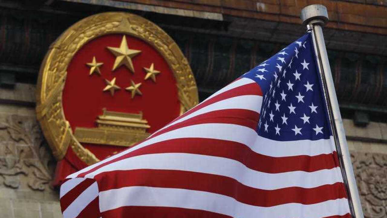 FILE - In this Nov. 9, 2017, file photo, an American flag is flown next to the Chinese national emblem during a welcome ceremony for visiting U.S. President Donald Trump outside the Great Hall of the People in Beijing.