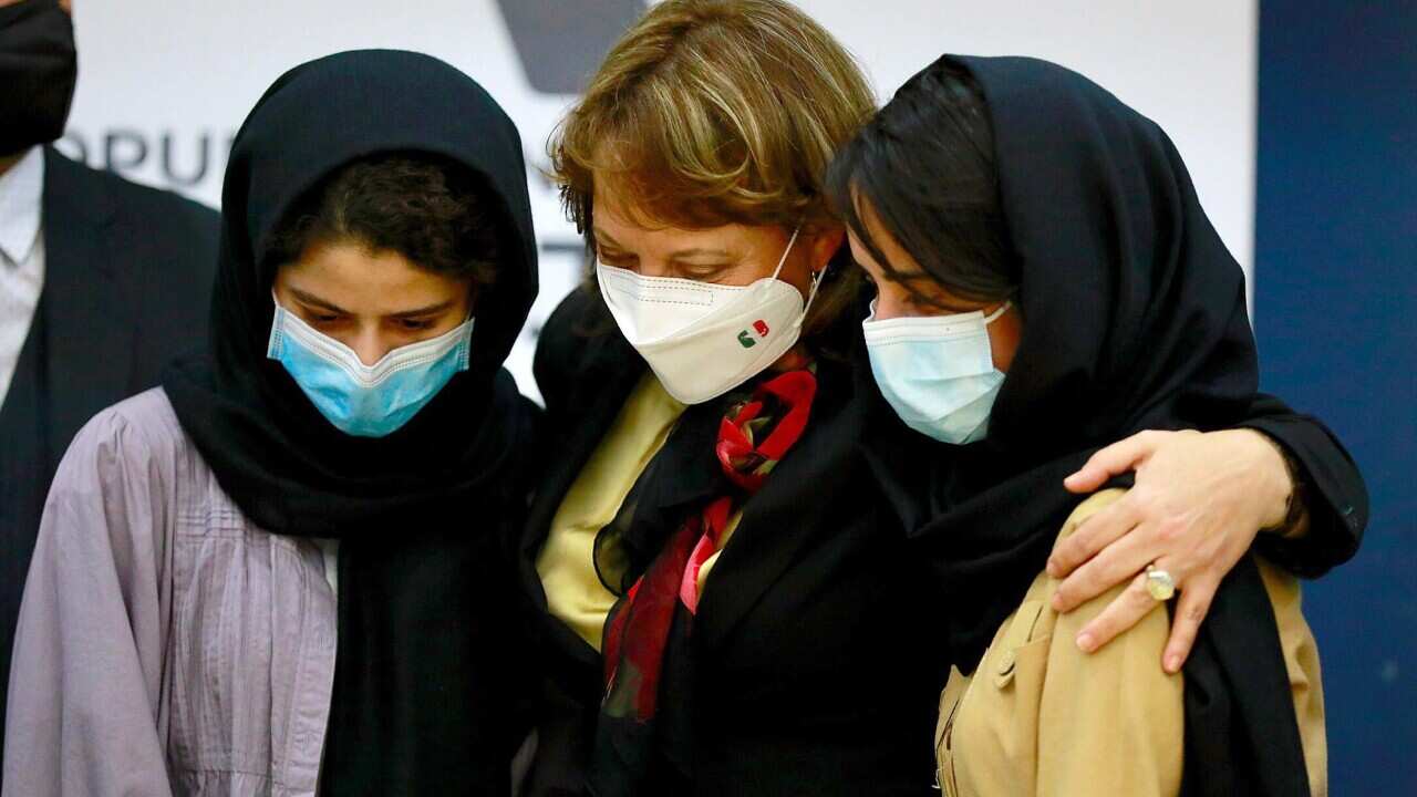 Mexican minister Martha Delgado (C) hugs two Afghan refugees part of an all-girls robotics team