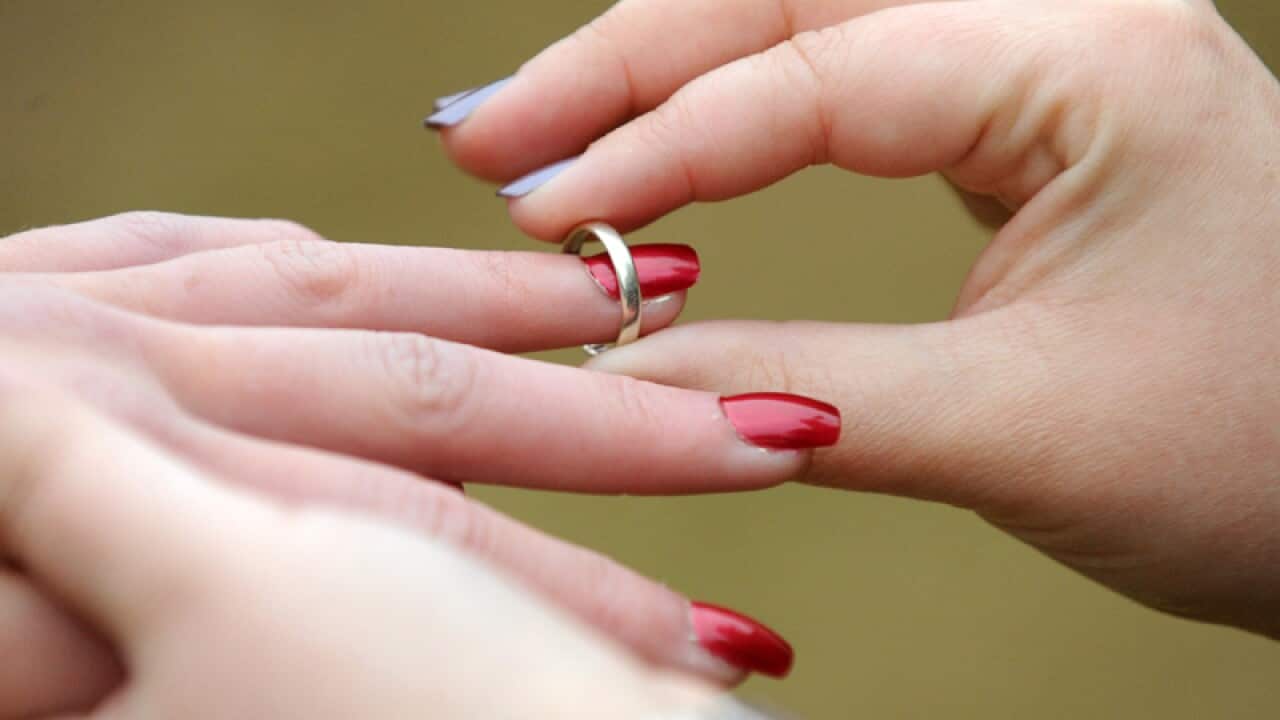 A woman places a wedding ring on her partners finger