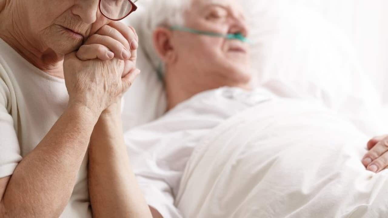 Senior man in hospital bed and his wife holding his hand