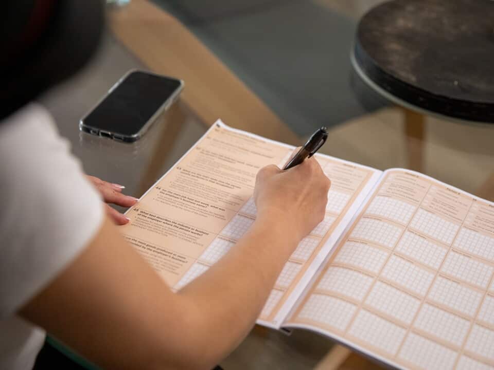 A4 Census booklet open on table, as a women uses a pen to fill in the form.