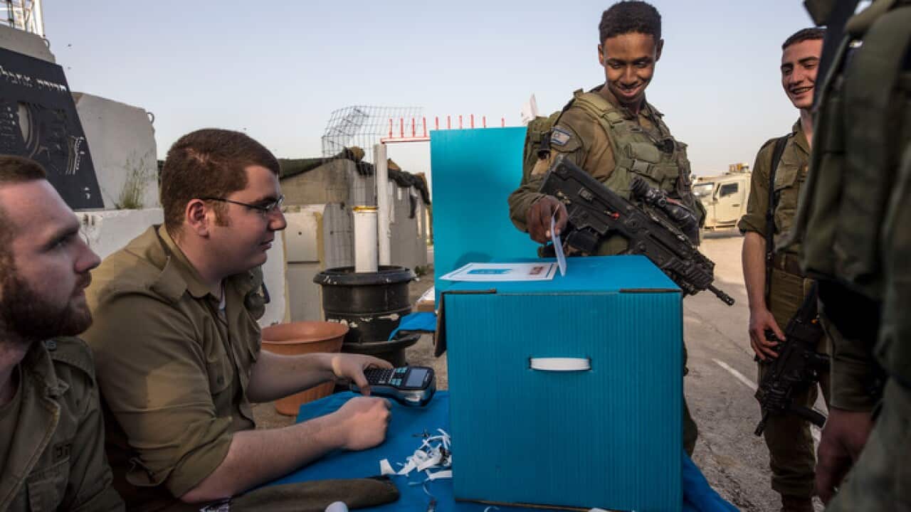 Israeli soldiers cast their early ballots at a mobile voting booth at a military post on the northern Israel and Gaza border