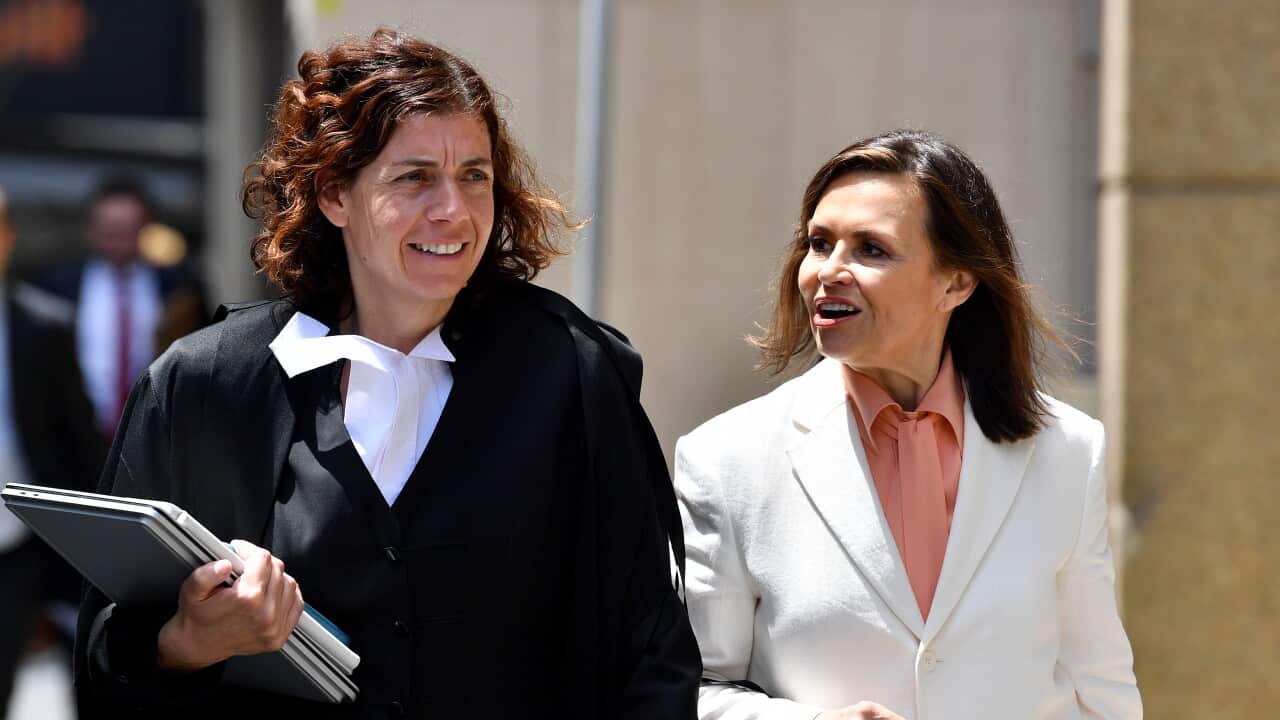 Two women wearing formal attire talking while walking outside.