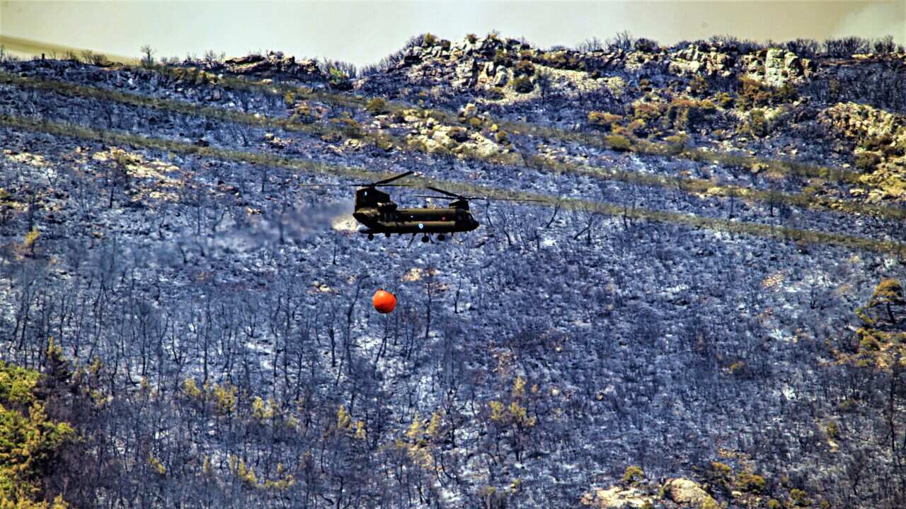 A military helicopter participates in a battle to extinguish a forest fire raging for the fourth day in the Dadia National Park, in Evros, northern Greece, 24 July 2022. Fire-fighting forces on the ground and in the air continued to battle the flames on 2