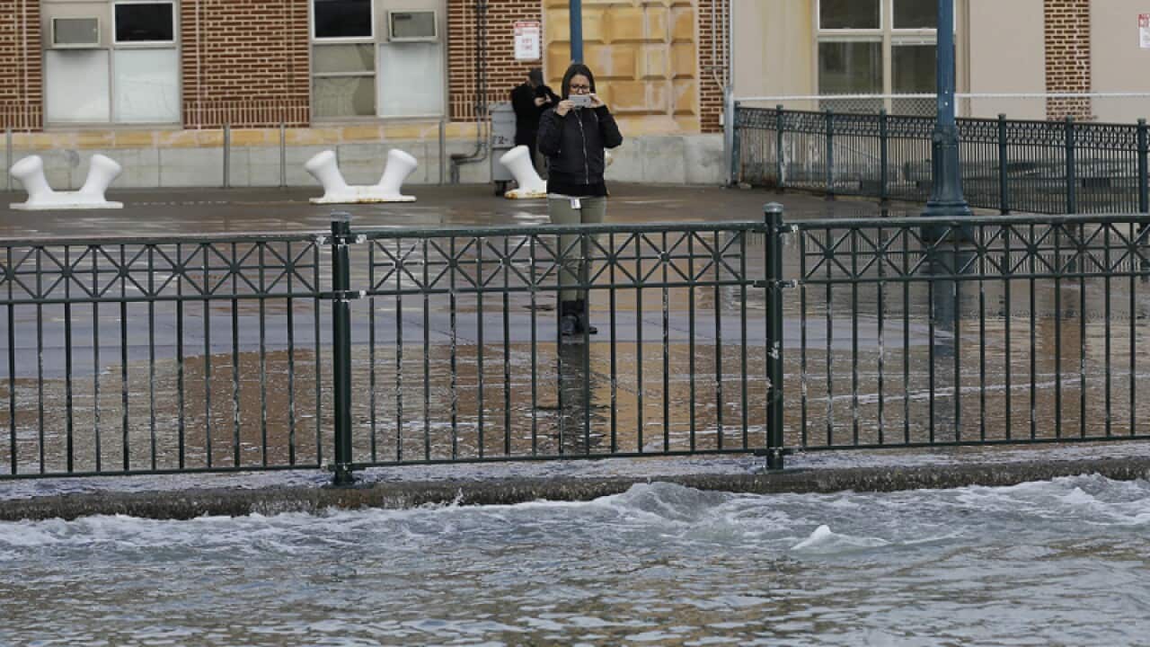 A woman takes a photo of water from a king tide