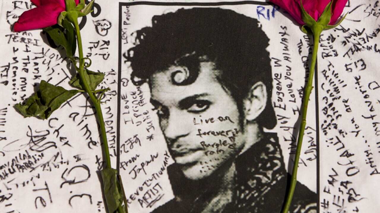 Flowers lay on a T-shirt signed by fans of singer Prince at a memorial