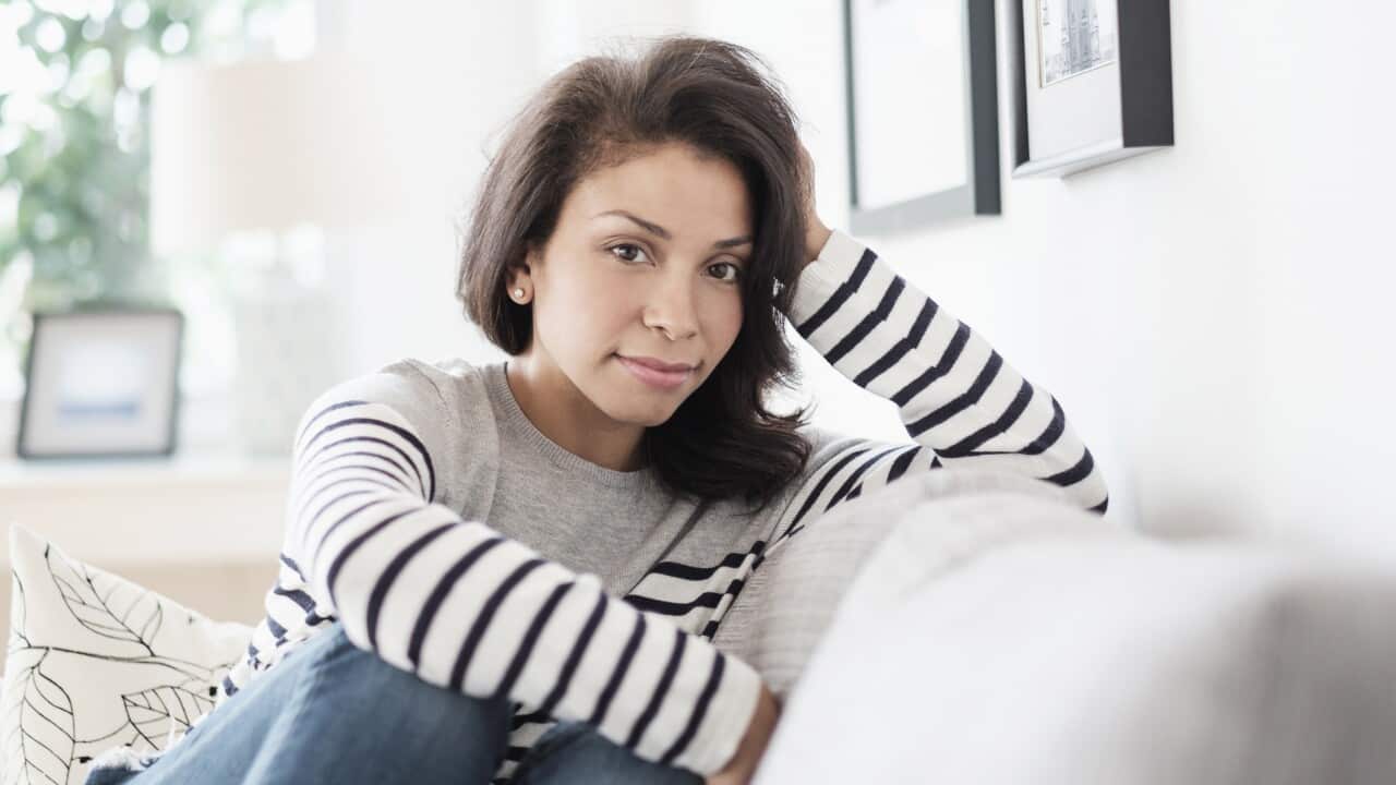 Mixed race woman sitting on sofa.
