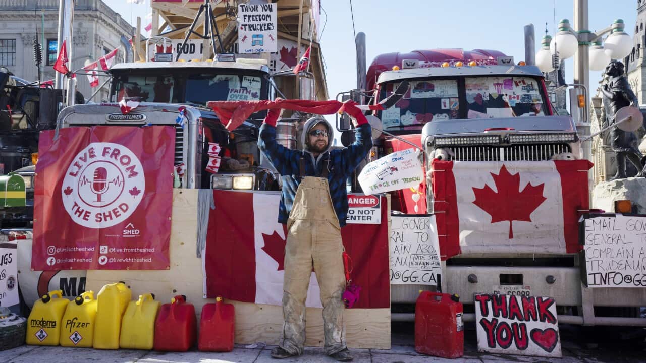 A protester holds a hockey stick wrapped in a Canadian flag above his head on Monday, 14 February, 2022 in Ottawa.
