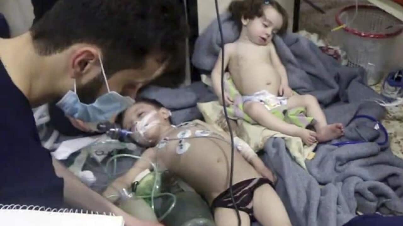 A medical worker treats toddlers after an alleged poison gas attack