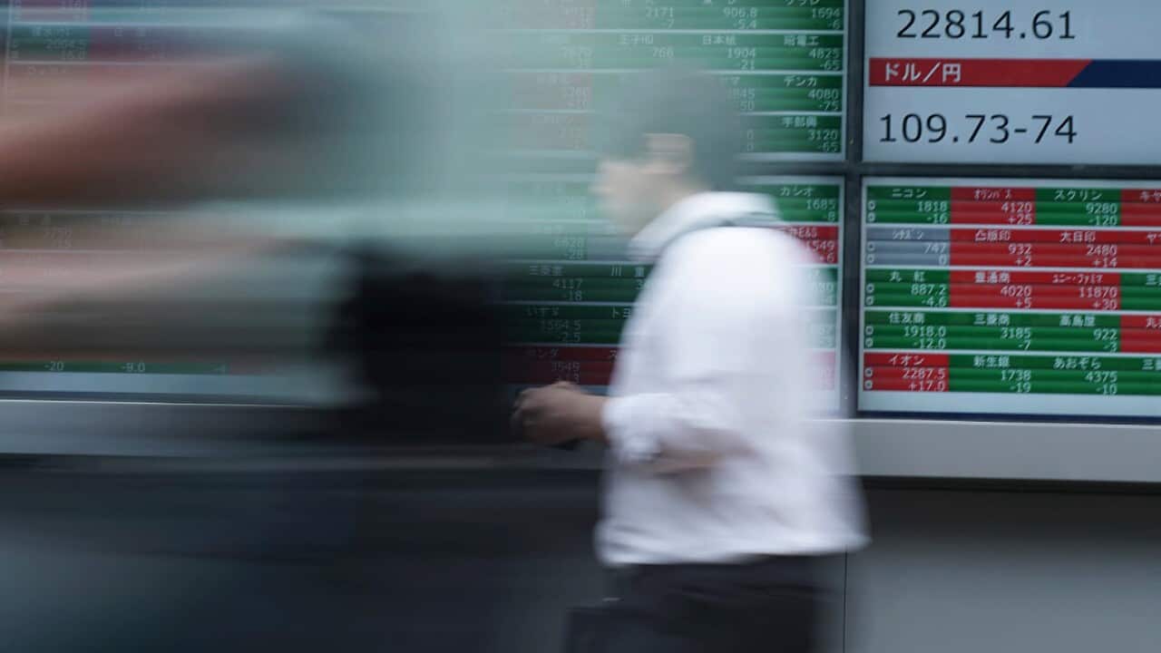 A man walks past an electronic stock board at a securities firm in Tokyo.