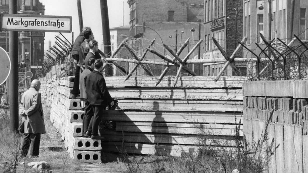 17. April 1964: Männer in West-Berlin blicken über die Mauer.