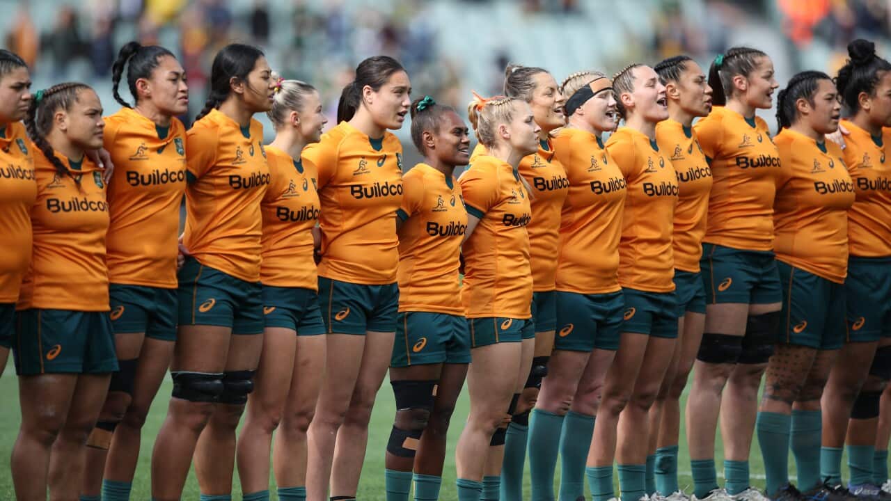 Women in gold rugby shirts standing in a line.