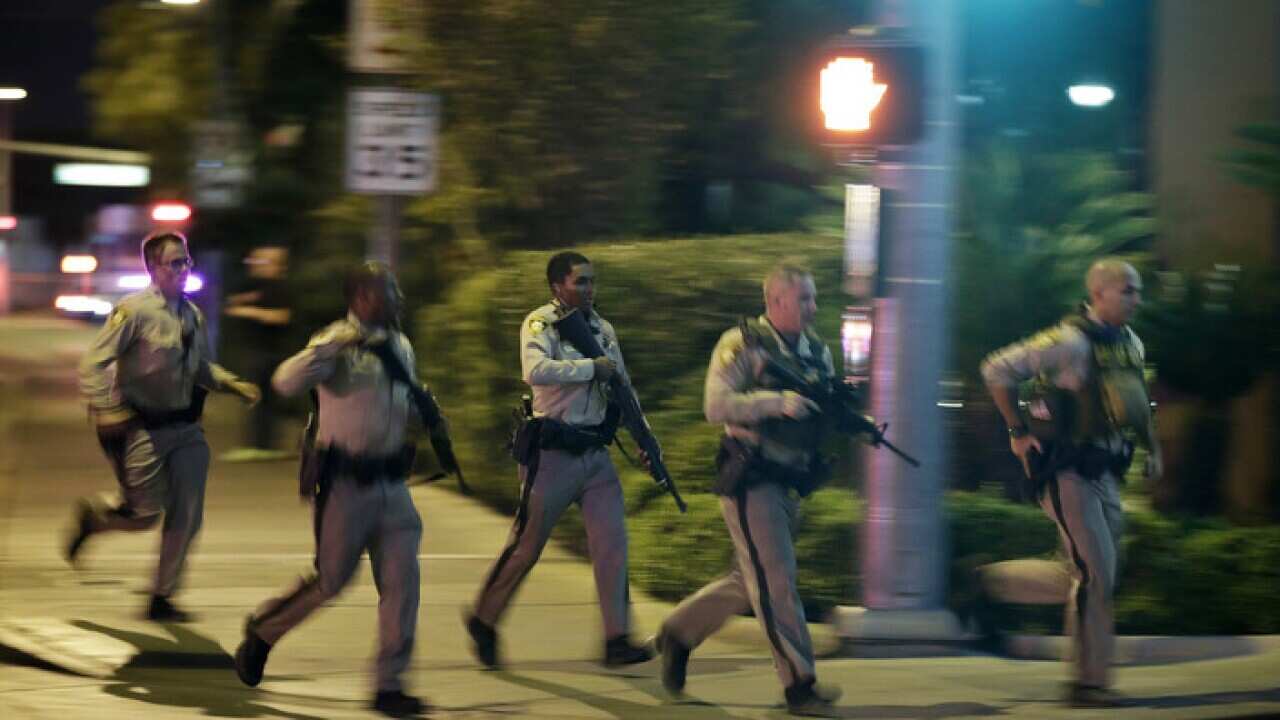Police run to cover at the scene of a shooting near the Mandalay Bay .