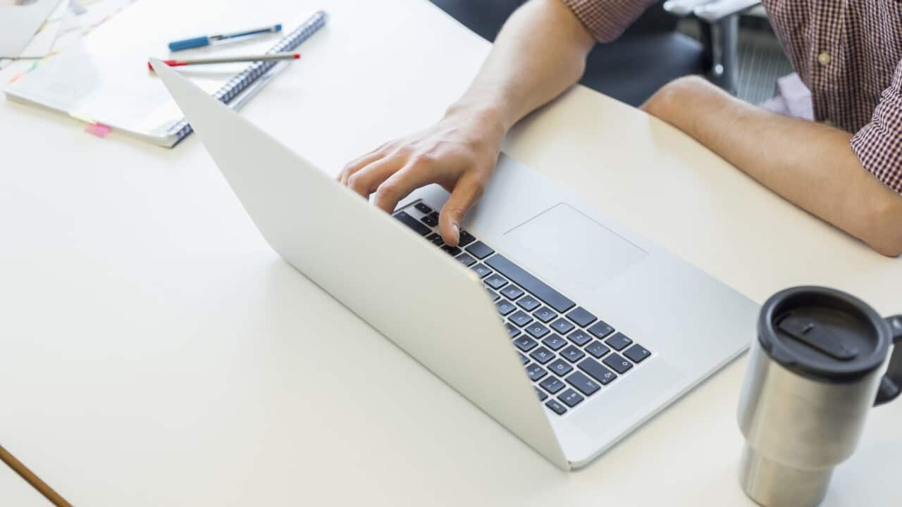 Cropped image of man using laptop at desk in creative office