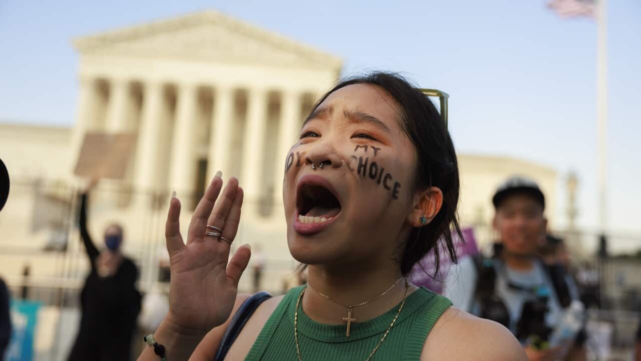 Robin Gwak screams chants outside Supreme Court with black paint on her cheeks that says, "my body, my choice".