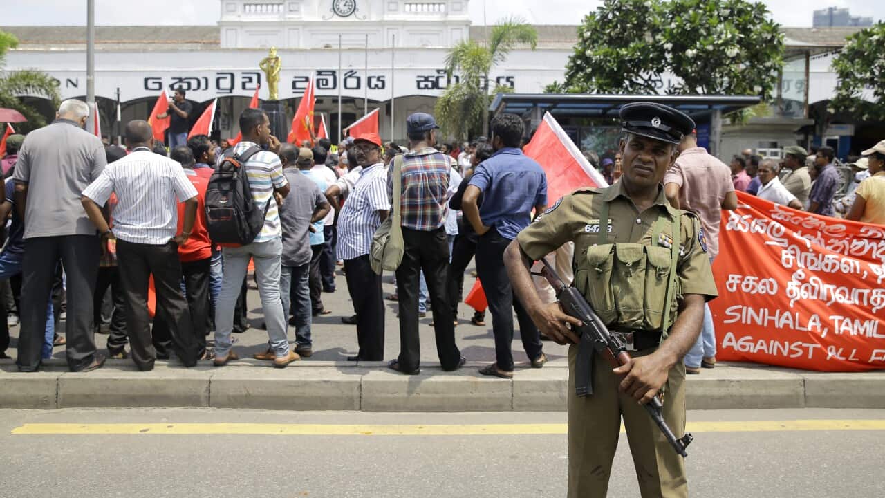 A Sri Lankan police officer secures the area of a labor day gathering.