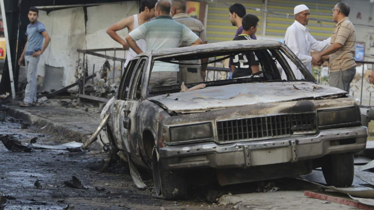 People inspect the aftermath of a car bomb in Baghdad, Iraq