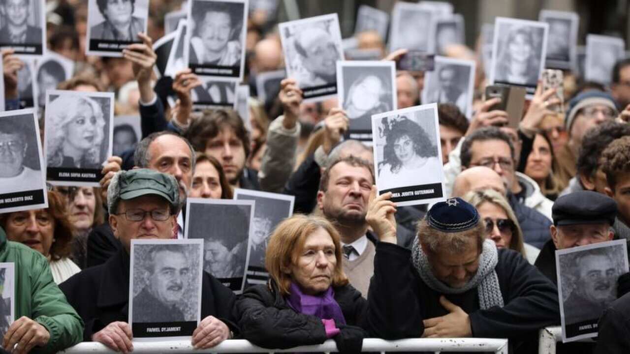 People hold up pictures of people who died during the bombing at the AMIA Jewish center that killed 85 people on the 25th anniversary of the attack in Buenos Aires, Argentina, Thursday, July 18, 2019. (AP Photo/Natacha Pisarenko)