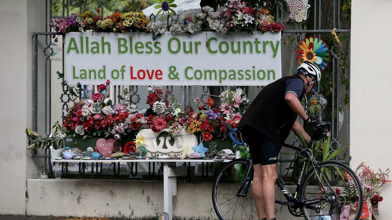 A cyclist stops to lays flowers at the entrance of the Al Noor Mosque.