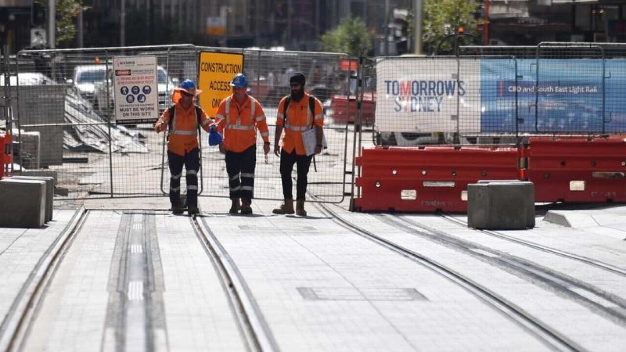 Workmen walk past the George St Sydney CBD Light Rail Project.