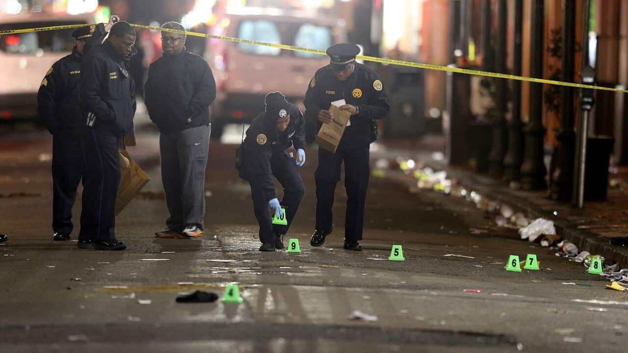 A crime scene technician collects evidence from the street as New Orleans Police investigate a fatal shooting at Iberville and Bourbon streets