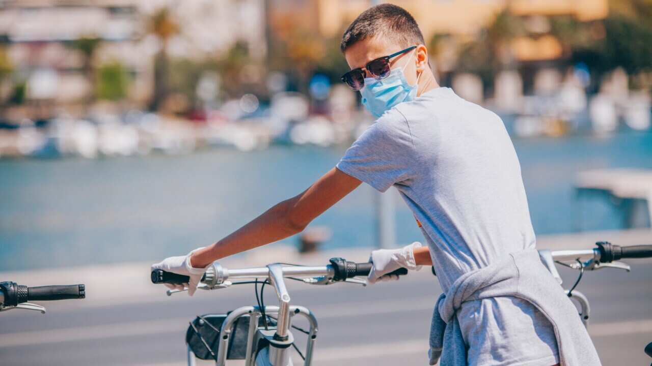 A tourist with protective mask and glove, rents a city bike from a self-service portal in Croatia.