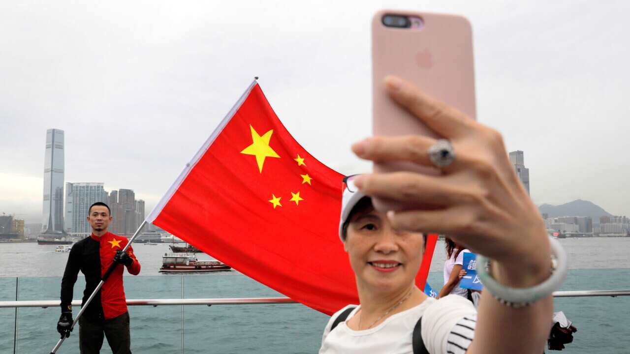 Pro-China supporters take a selfie with a Chinese national flag during a rally at a park in Hong Kong