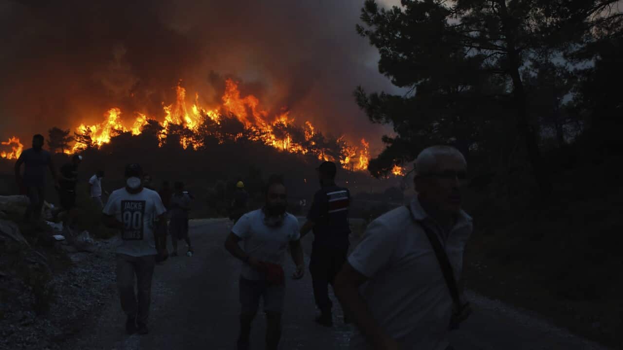 People walk away from a wildfire near Akcayaka village in Milas, Mugla in southwest Turkey.