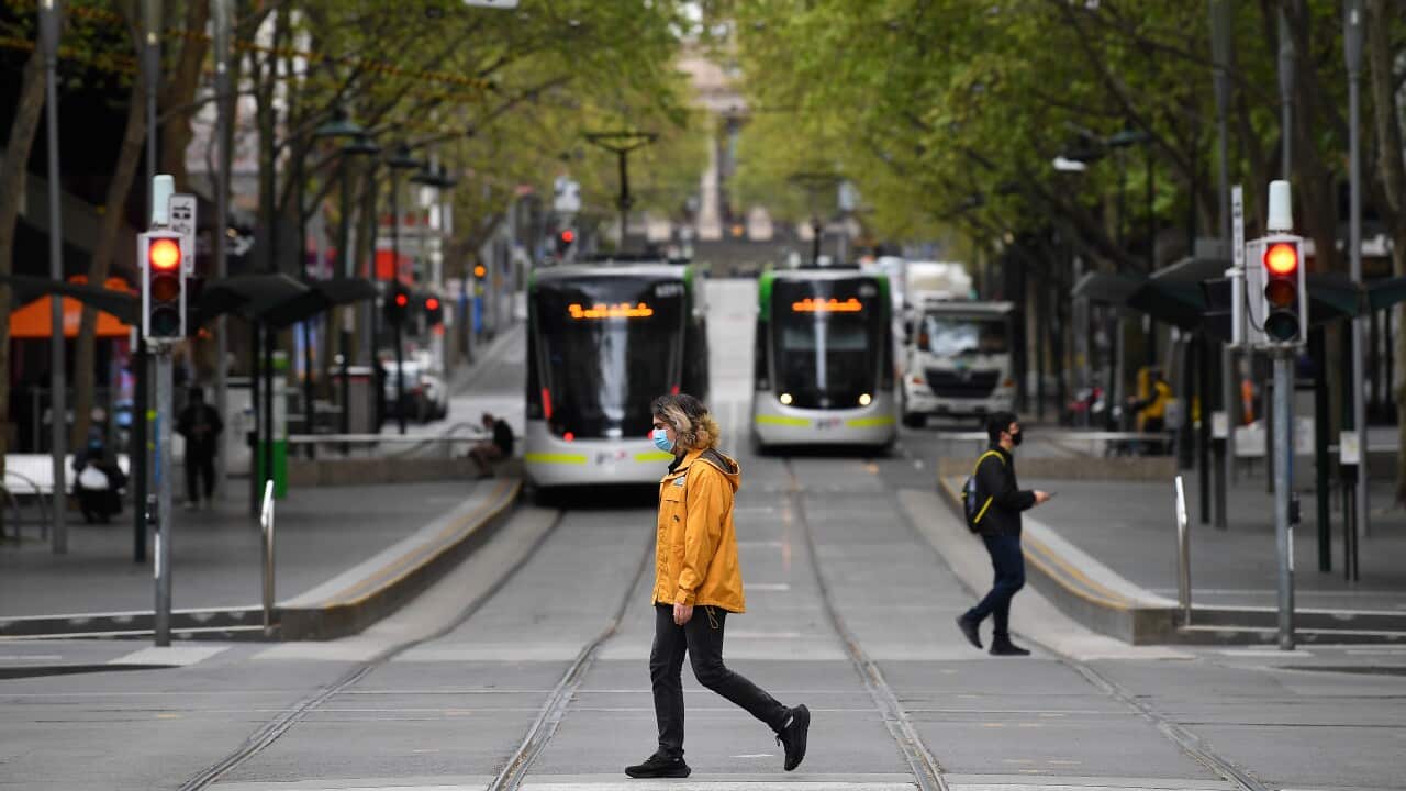 A person wearing a face mask crosses a street in Melbourne.