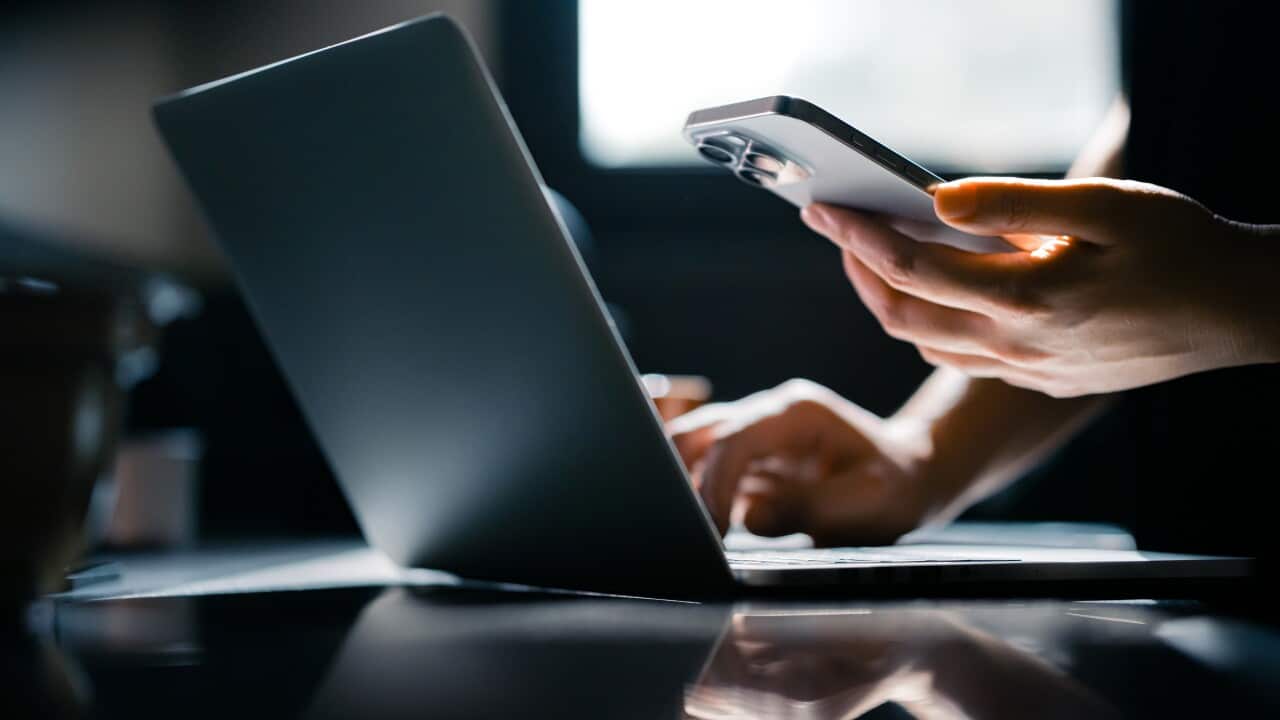 Close-up shot of a woman using mobile device with Two-Factor Authentication (2FA) security while logging in securely to her laptop